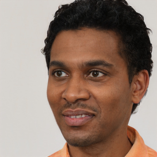 Joyful black young-adult male with short  black hair and brown eyes