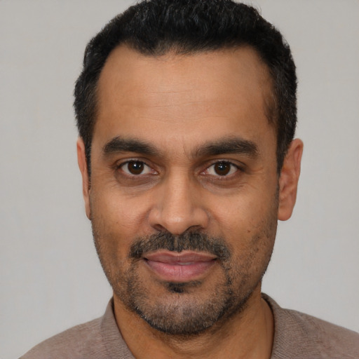 Joyful latino adult male with short  black hair and brown eyes