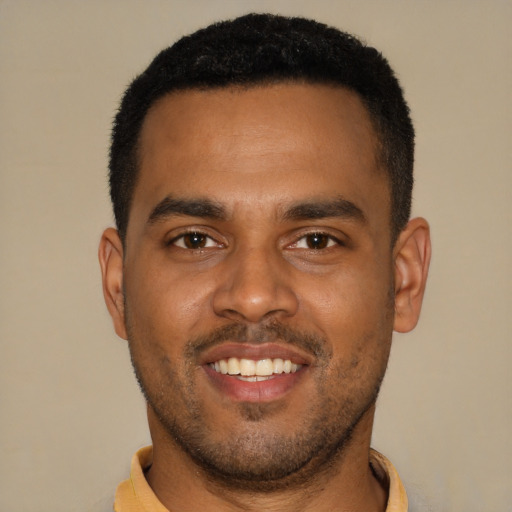 Joyful black young-adult male with short  brown hair and brown eyes