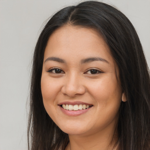 Joyful latino young-adult female with long  brown hair and brown eyes