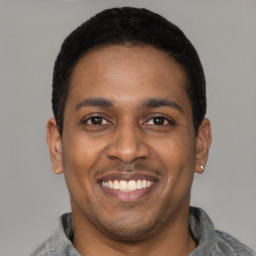Joyful latino young-adult male with short  black hair and brown eyes