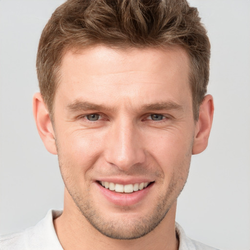 Joyful white young-adult male with short  brown hair and grey eyes