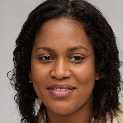 Joyful black young-adult female with long  brown hair and brown eyes