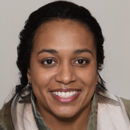 Joyful black young-adult female with long  brown hair and brown eyes