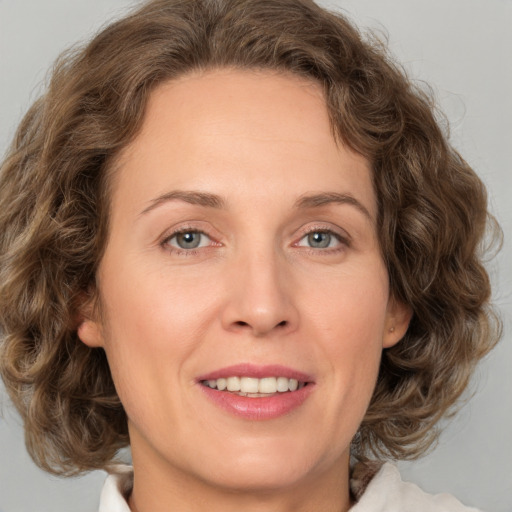 Joyful white adult female with medium  brown hair and green eyes