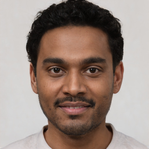 Joyful black young-adult male with short  black hair and brown eyes