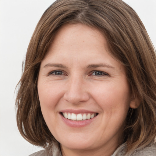 Joyful white young-adult female with medium  brown hair and grey eyes