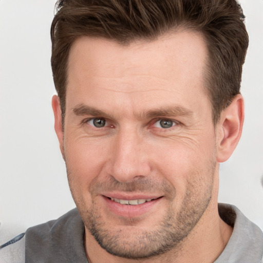 Joyful white adult male with short  brown hair and grey eyes