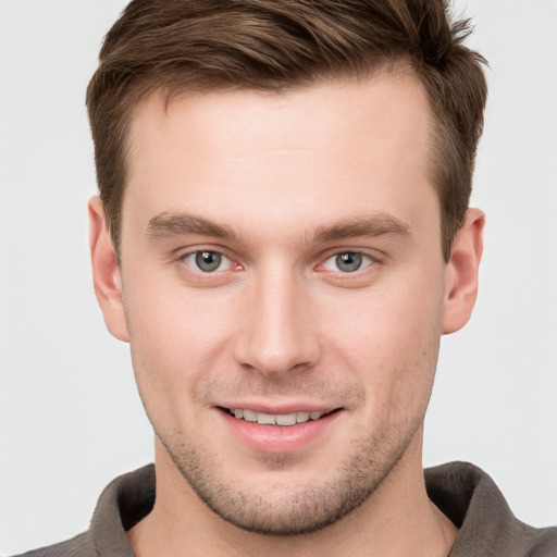 Joyful white young-adult male with short  brown hair and grey eyes