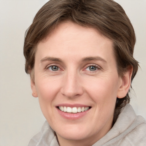 Joyful white young-adult female with medium  brown hair and grey eyes