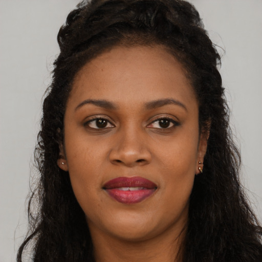 Joyful black young-adult female with long  brown hair and brown eyes