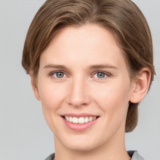 Joyful white young-adult female with medium  brown hair and grey eyes