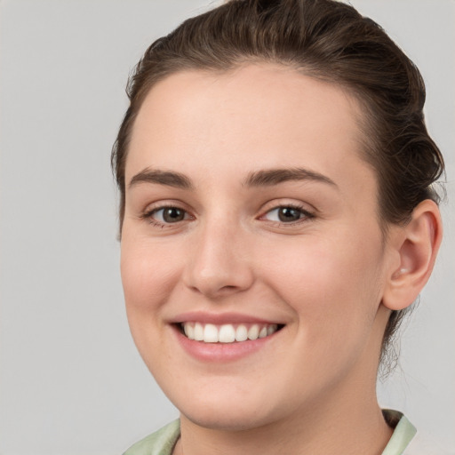 Joyful white young-adult female with medium  brown hair and grey eyes