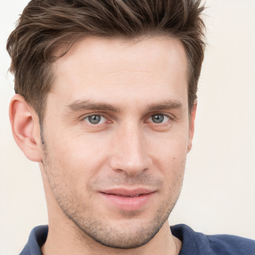 Joyful white young-adult male with short  brown hair and grey eyes