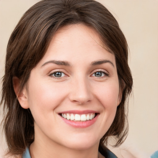 Joyful white young-adult female with medium  brown hair and grey eyes