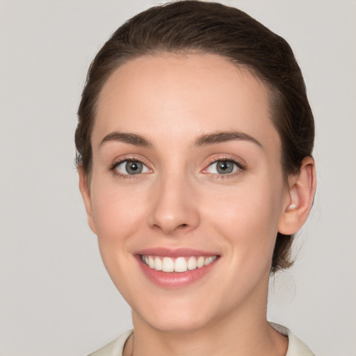 Joyful white young-adult female with medium  brown hair and grey eyes