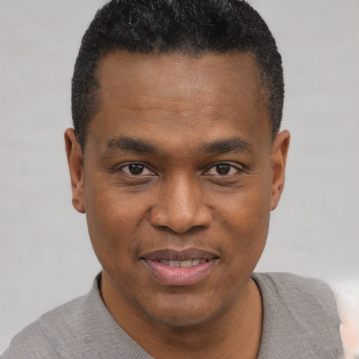 Joyful black young-adult male with short  black hair and brown eyes