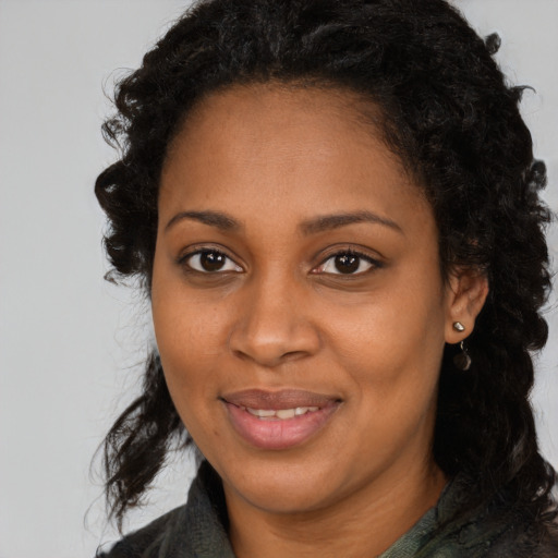 Joyful black young-adult female with long  brown hair and brown eyes