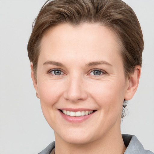 Joyful white young-adult female with short  brown hair and grey eyes