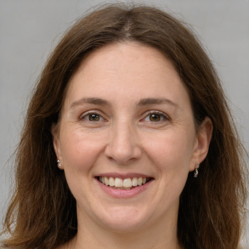 Joyful white adult female with long  brown hair and grey eyes