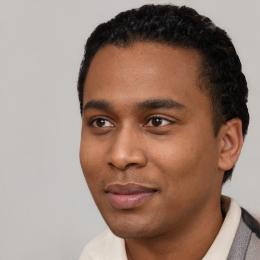 Joyful black young-adult male with short  black hair and brown eyes