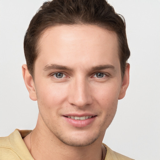 Joyful white young-adult male with short  brown hair and grey eyes