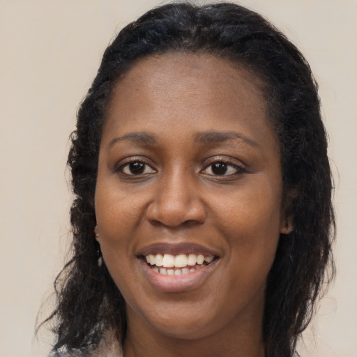 Joyful black young-adult female with long  brown hair and brown eyes