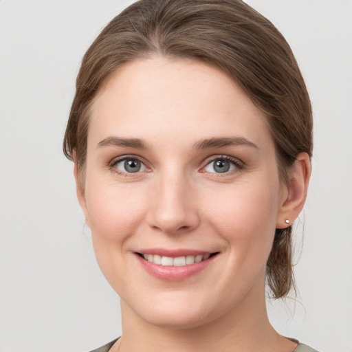 Joyful white young-adult female with medium  brown hair and grey eyes