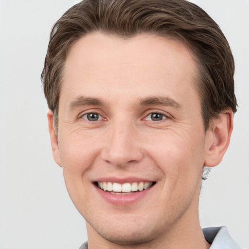 Joyful white young-adult male with short  brown hair and grey eyes