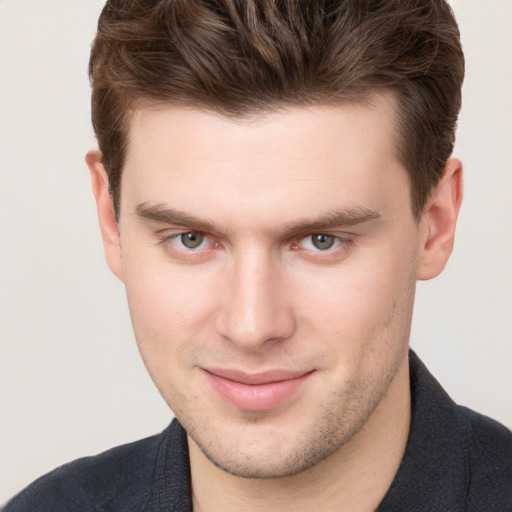 Joyful white young-adult male with short  brown hair and grey eyes