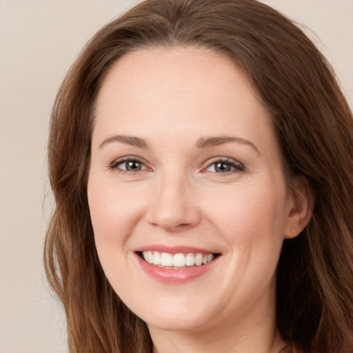 Joyful white young-adult female with long  brown hair and grey eyes