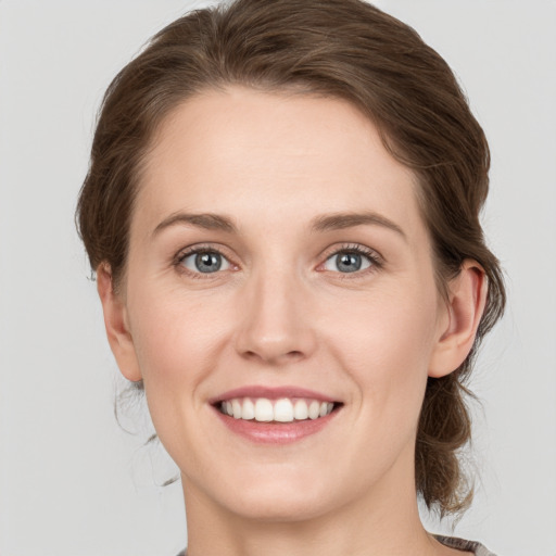 Joyful white young-adult female with medium  brown hair and grey eyes