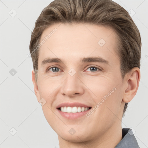 Joyful white young-adult male with short  brown hair and grey eyes