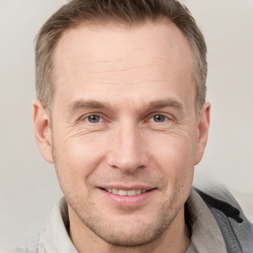 Joyful white adult male with short  brown hair and grey eyes