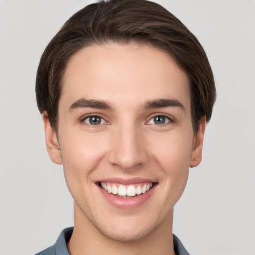 Joyful white young-adult male with short  brown hair and grey eyes