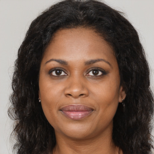 Joyful black adult female with long  brown hair and brown eyes