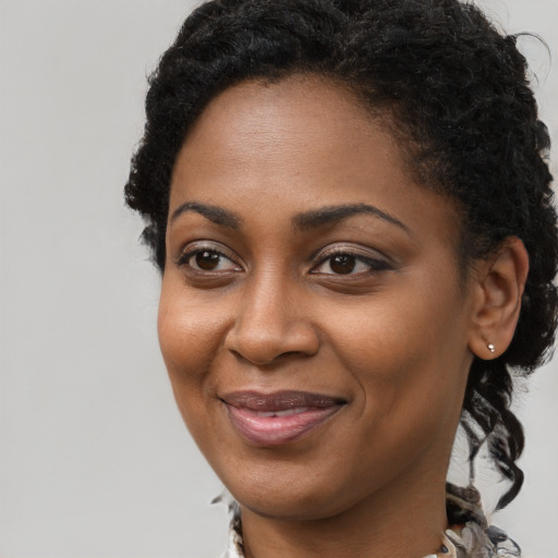 Joyful black young-adult female with long  brown hair and brown eyes