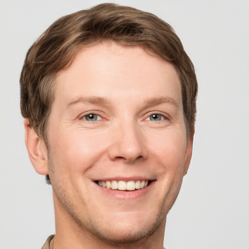 Joyful white young-adult male with short  brown hair and grey eyes