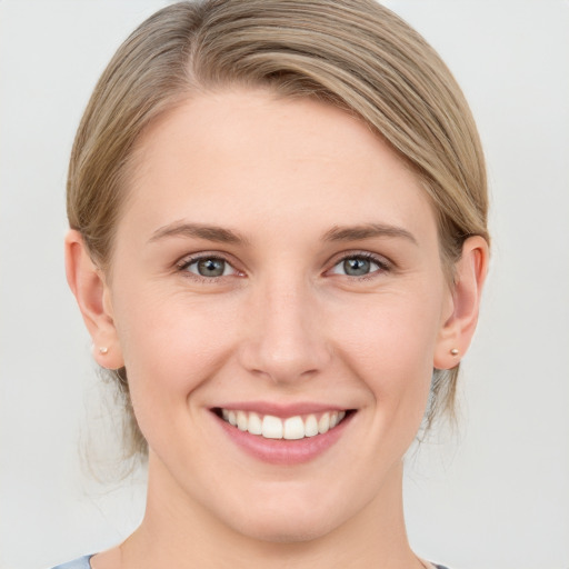 Joyful white young-adult female with medium  brown hair and grey eyes