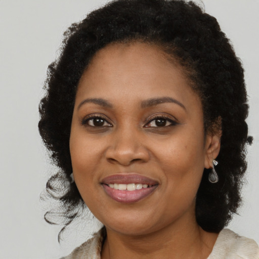 Joyful black young-adult female with long  brown hair and brown eyes