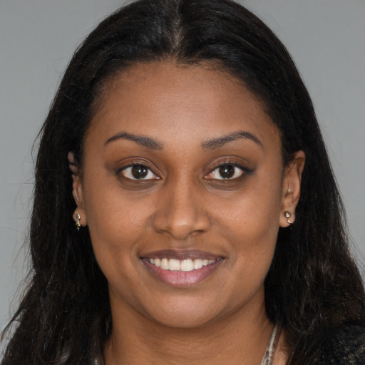 Joyful black young-adult female with long  brown hair and brown eyes