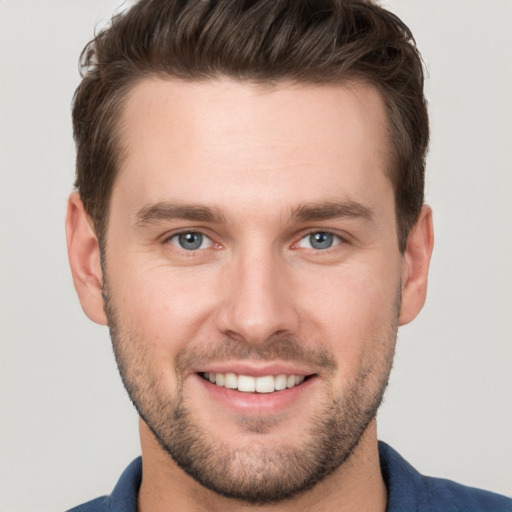 Joyful white young-adult male with short  brown hair and grey eyes