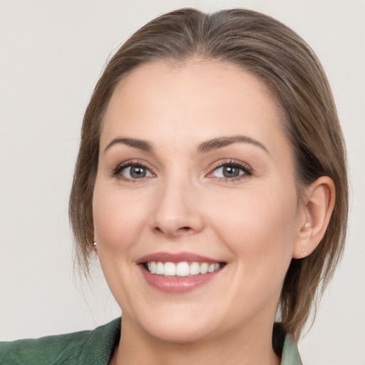 Joyful white young-adult female with medium  brown hair and grey eyes