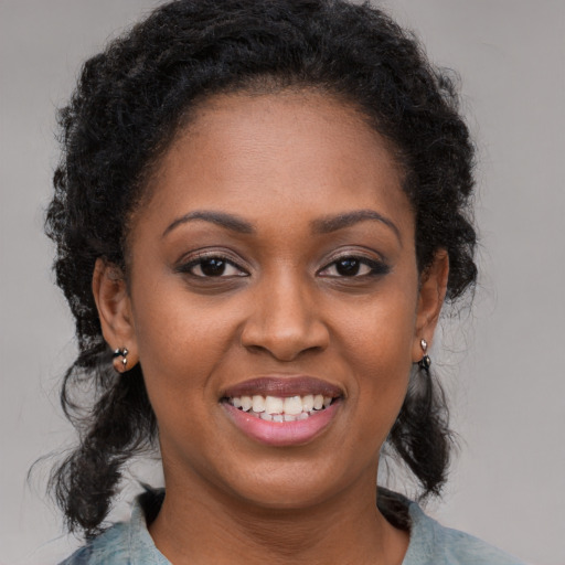 Joyful black young-adult female with long  brown hair and brown eyes