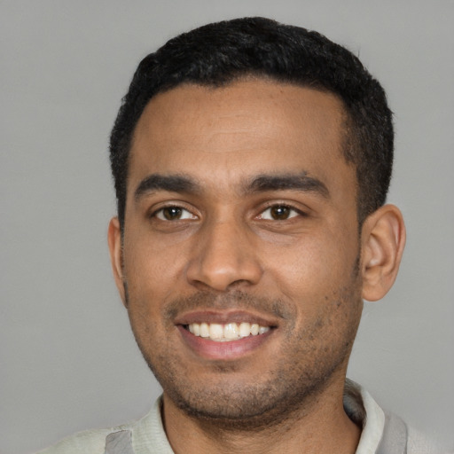 Joyful black young-adult male with short  black hair and brown eyes