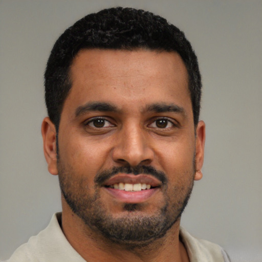 Joyful black young-adult male with short  black hair and brown eyes