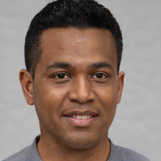 Joyful black young-adult male with short  black hair and brown eyes