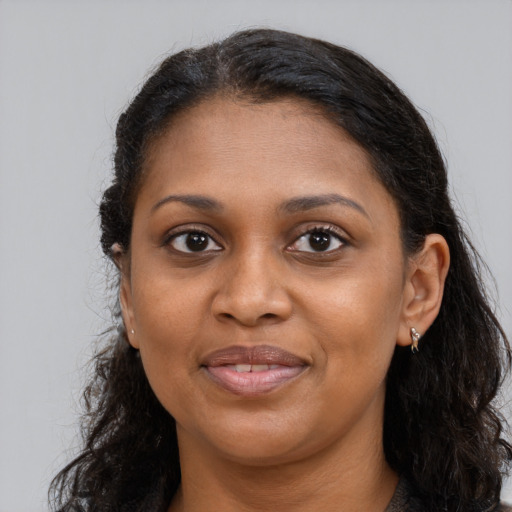 Joyful black young-adult female with long  brown hair and brown eyes