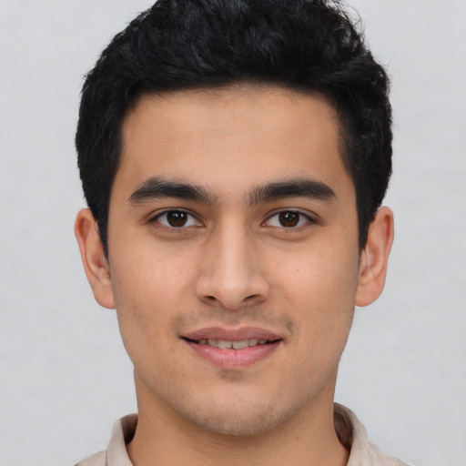 Joyful latino young-adult male with short  black hair and brown eyes