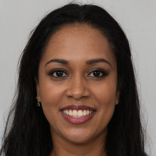 Joyful black young-adult female with long  brown hair and brown eyes